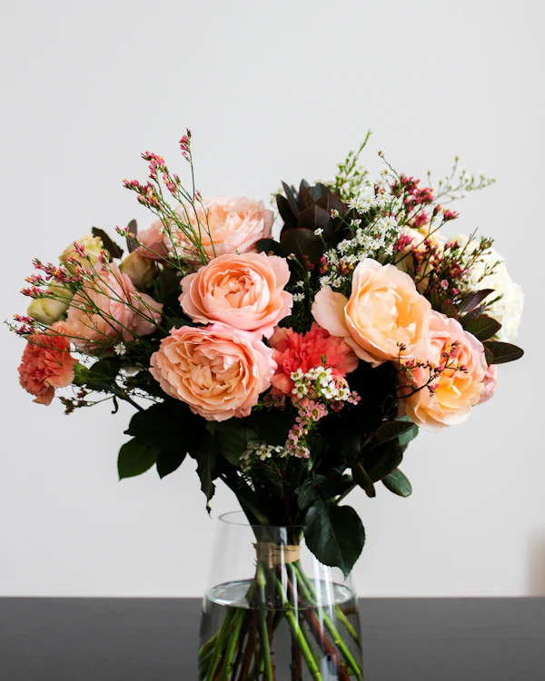 Strauß aus apricotfarbenen Rosen in einer Glasvase