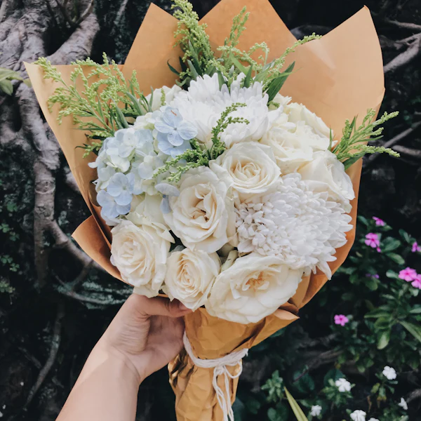 Strauß aus weißen Rosen und Hortensien in Packpapier