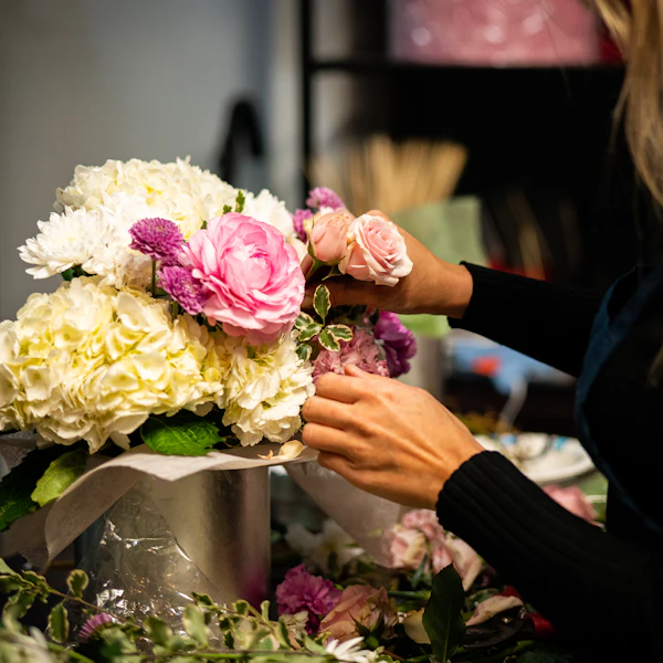 Hände stecken Rosen und Hortensien in eine Vase